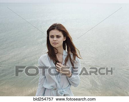 Stock Photo - Serious Caucasian woman standing near ocean. Fotosearch