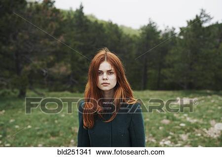Stock Image - Serious Caucasian woman wearing coat in field. Fotosearch