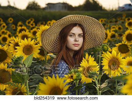Stock Photo - Serious Caucasian woman wearing hat in field of sunflowers. Fotosearch