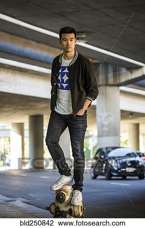 Stock Image - Serious Chinese man standing on hydrant. Fotosearch