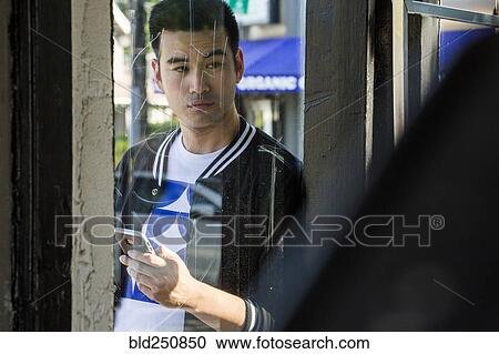 Serious Chinese man texting on cell phone behind window View Large Photo Image Stock Image - Serious Chinese man texting on cell phone behind window. Fotosearch