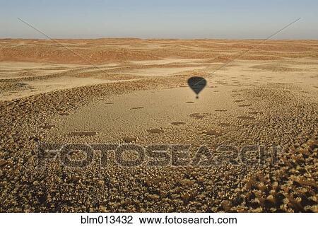 Stock Image - Shadow of hot air balloon over desert. Fotosearch