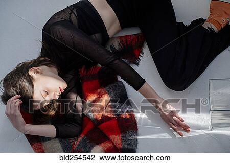 Stock Image - Shadow on Caucasian woman laying on floor. Fotosearch
