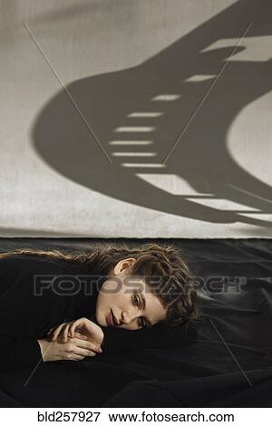 Stock Photo - Shadow on wall over pensive Caucasian woman. Fotosearch