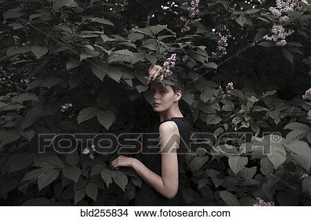 Shy Caucasian woman standing in flowering tree View Large Photo Image Picture - Shy Caucasian woman standing in flowering tree. Fotosearch