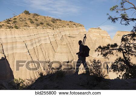 Stock Image - Silhouette of Caucasian man carrying tripod in desert. Fotosearch