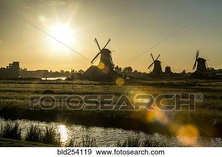 Stock Photo - Silhouette of windmills at waterfront. Fotosearch