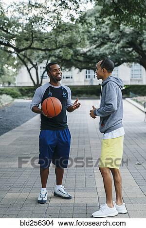 Picture - Smiling Black men holding basketball and taking. Fotosearch
