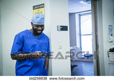 Stock Photo - Smiling black nurse texting on cell phone. Fotosearch