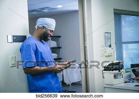 Stock Photo - Smiling black nurse using digital tablet. Fotosearch