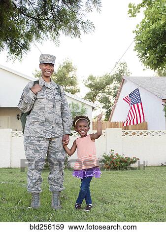 Stock Photo - Smiling black woman soldier with daughter waving American flag. Fotosearch
