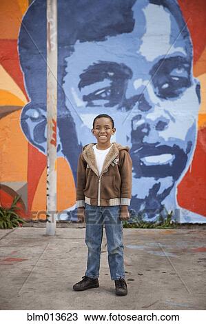 Stock Image - Smiling boy standing by mural. Fotosearch