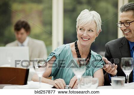 Stock Photo - Smiling business people working at table in restaurant. Fotosearch