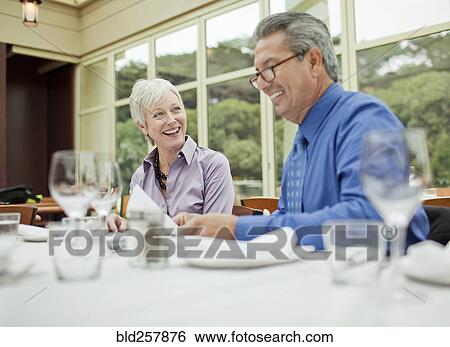 Stock Photograph - Smiling business people working at table in restaurant. Fotosearch