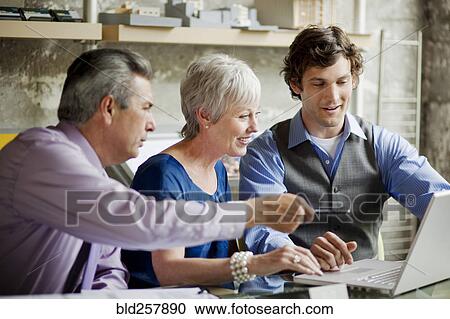 Smiling businesspeople using laptop in office View Large Photo Image Stock Image - Smiling businesspeople using laptop in office. Fotosearch