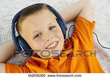 Smiling Caucasian boy laying on blanket in park listening to headphones View Large Photo Image Stock Image - Smiling Caucasian boy laying on blanket in park listening to headphones. Fotosearch