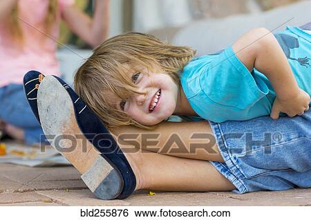 Smiling Caucasian boy laying on legs of mother View Large Photo Image Stock Photograph - Smiling Caucasian boy laying on legs of mother. Fotosearch