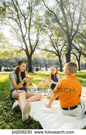 Smiling Caucasian brother and sisters eating food at picnic View Large Photo Image Stock Image - Smiling Caucasian brother and sisters eating food at picnic. Fotosearch