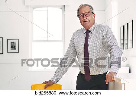 Stock Image - Smiling Caucasian businessman leaning on chair. Fotosearch