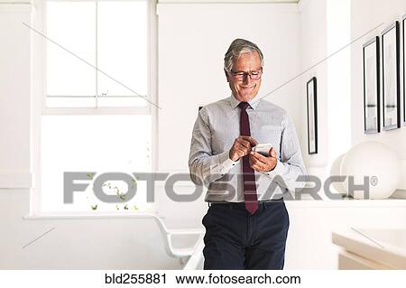 Stock Image - Smiling Caucasian businessman texting on cell phone. Fotosearch