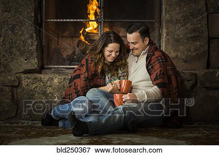 Smiling Caucasian couple cuddling on floor near fireplace View Large Photo Image Stock Photo - Smiling Caucasian couple cuddling on floor near fireplace. Fotosearch