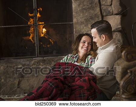 Smiling Caucasian couple cuddling on floor near fireplace View Large Photo Image Stock Photo - Smiling Caucasian couple cuddling on floor near fireplace. Fotosearch