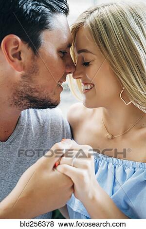Stock Photo - Smiling Caucasian couple holding hands and rubbing noses. Fotosearch