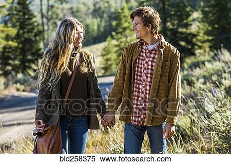 Stock Photography - Smiling Caucasian couple holding hands outdoors. Fotosearch
