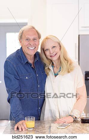 Stock Image - Smiling Caucasian couple posing in kitchen. Fotosearch
