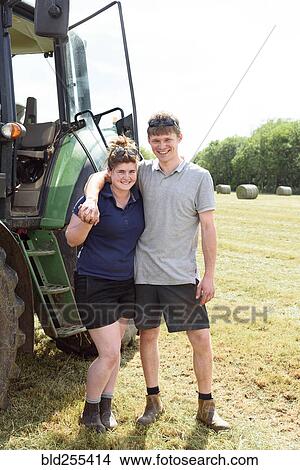 Picture - Smiling Caucasian couple posing near tractor. Fotosearch