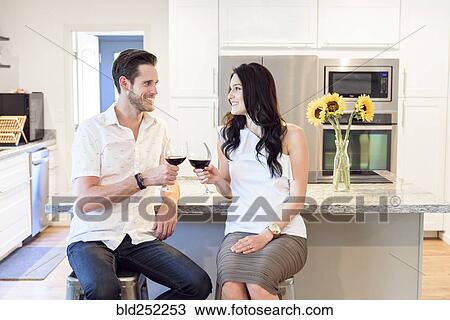 Stock Image - Smiling Caucasian couple toasting with red wine. Fotosearch