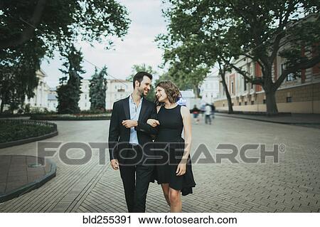 Stock Image - Smiling Caucasian couple walking arm in arm. Fotosearch