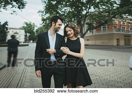 Stock Image - Smiling Caucasian couple walking arm in arm. Fotosearch