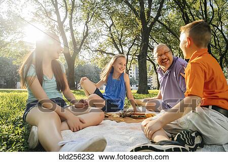 Smiling Caucasian family eating food at picnic View Large Photo Image Stock Image - Smiling Caucasian family eating food at picnic. Fotosearch
