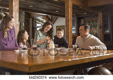 Picture - Smiling Caucasian family eating meal at table. Fotosearch