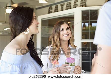 Smiling Caucasian friends with cold drinks talking outdoors View Large Photo Image Stock Photography - Smiling Caucasian friends with cold drinks talking outdoors. Fotosearch