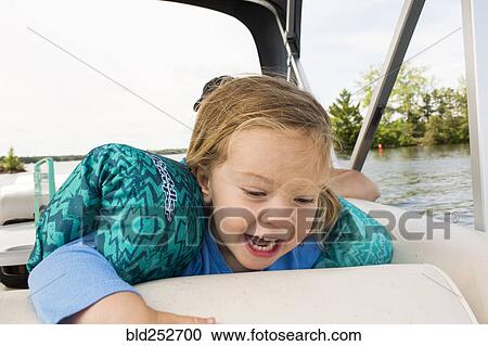 Stock Image - Smiling Caucasian girl on boat. Fotosearch