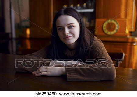 Stock Image - Smiling Caucasian girl sitting at table. Fotosearch