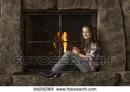 Smiling Caucasian girl sitting near fireplace View Large Photo Image Picture - Smiling Caucasian girl sitting near fireplace. Fotosearch