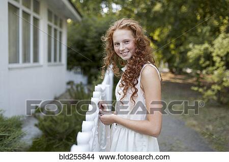 Picture - Smiling Caucasian girl standing near fence. Fotosearch