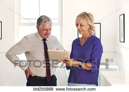 Smiling Caucasian man and woman using digital tablet View Large Photo Image Stock Photo - Smiling Caucasian man and woman using digital tablet. Fotosearch