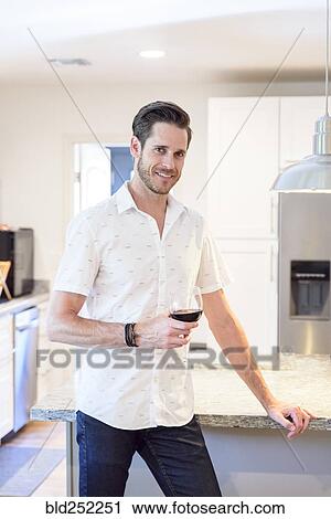 Stock Image - Smiling Caucasian man drinking red wine. Fotosearch