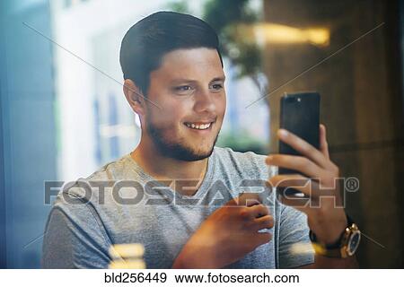 Stock Photo - Smiling Caucasian man posing for cell phone selfie. Fotosearch