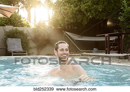 Stock Photo - Smiling Caucasian man relaxing in swimming pool. Fotosearch