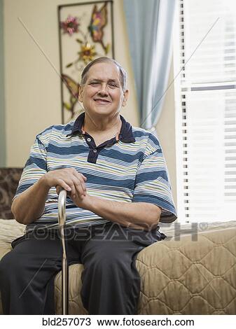 Smiling Caucasian man sitting on bed holding cane View Large Photo Image Stock Image - Smiling Caucasian man sitting on bed holding cane. Fotosearch