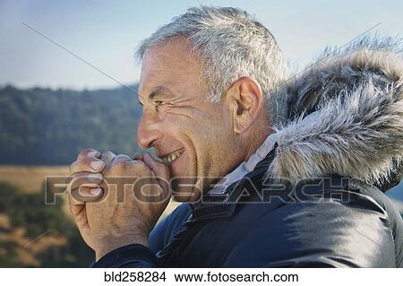 Picture - Smiling Caucasian man wearing coat with fur hood. Fotosearch