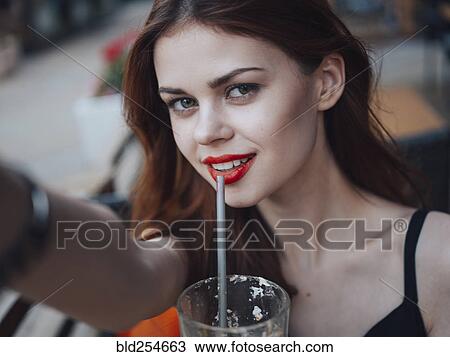 Smiling Caucasian woman drinking from straw posing for selfie View Large Photo Image Stock Image - Smiling Caucasian woman drinking from straw posing for selfie. Fotosearch