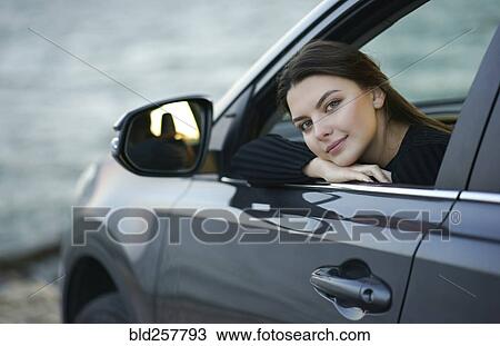 Stock Image - Smiling Caucasian woman leaning in car window. Fotosearch