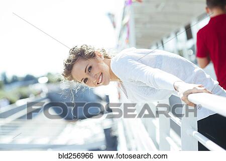 Stock Photograph - Smiling Caucasian woman leaning over railing. Fotosearch