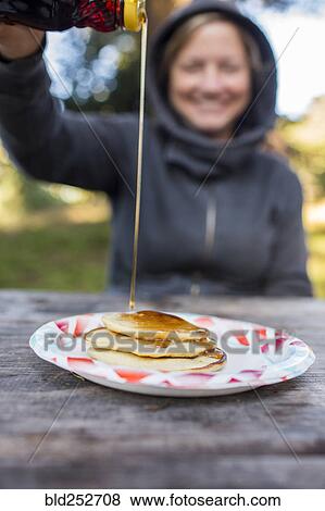 Smiling Caucasian woman pouring syrup on pancakes View Large Photo Image Stock Photo - Smiling Caucasian woman pouring syrup on pancakes. Fotosearch